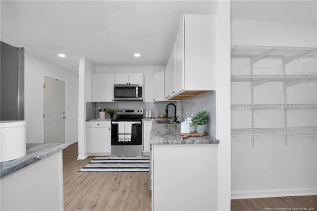 kitchen with tasteful backsplash, white cabinetry, sink, and stainless steel appliances