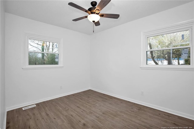 spare room featuring plenty of natural light, dark wood-type flooring, and ceiling fan