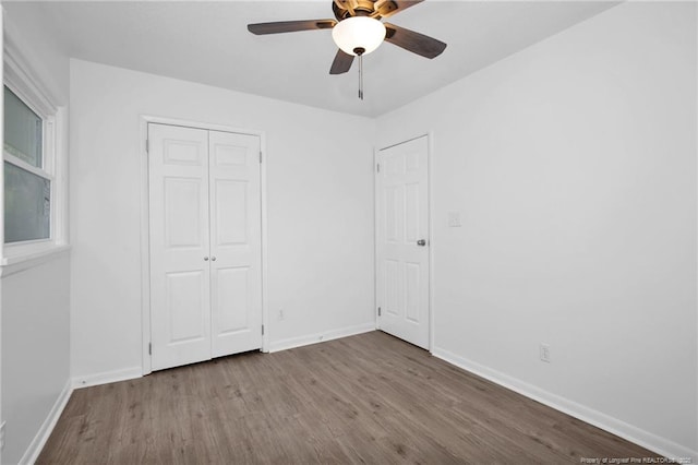 unfurnished bedroom with hardwood / wood-style floors, a closet, and ceiling fan