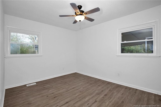 unfurnished room with a wealth of natural light, ceiling fan, and dark wood-type flooring