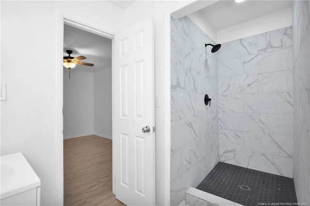 bathroom with a tile shower, vanity, ceiling fan, and hardwood / wood-style floors