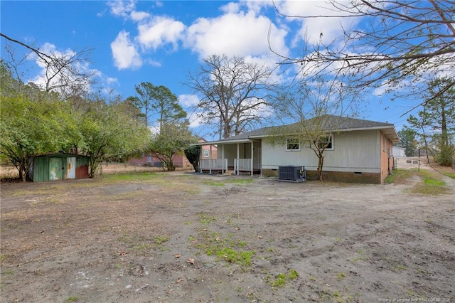 rear view of property featuring central AC, covered porch, and a storage unit