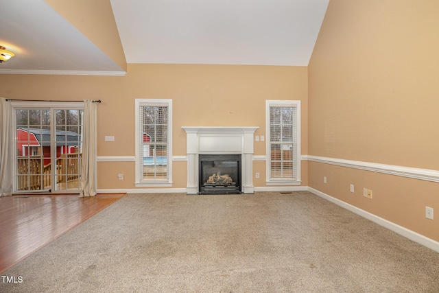 unfurnished living room with lofted ceiling, carpet floors, and crown molding