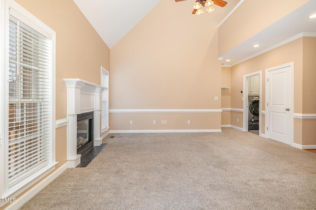 unfurnished living room with vaulted ceiling, carpet, ornamental molding, ceiling fan, and washer / dryer