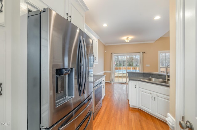 kitchen featuring light hardwood / wood-style flooring, crown molding, white cabinets, appliances with stainless steel finishes, and sink