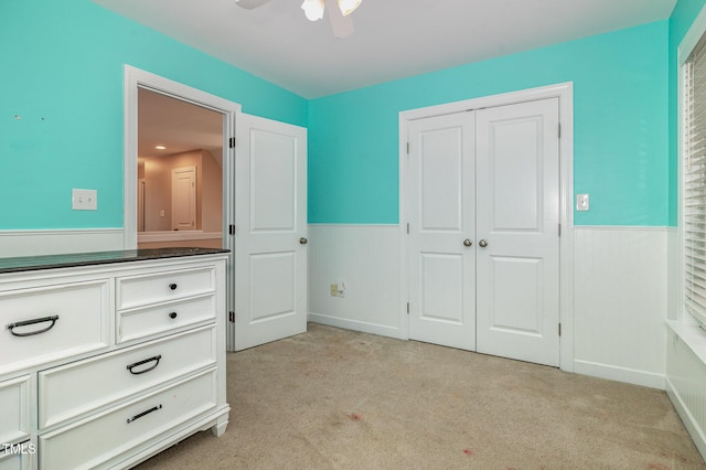 unfurnished bedroom featuring ceiling fan, a closet, and light carpet