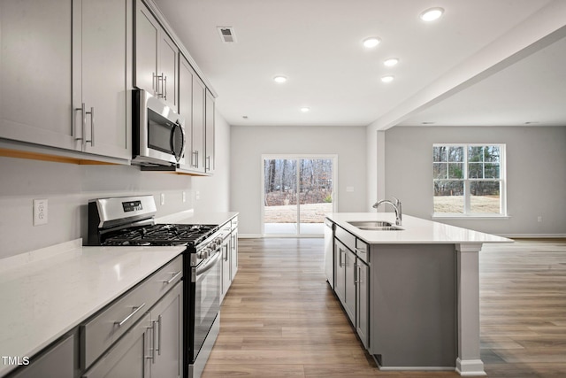 kitchen with stainless steel appliances, gray cabinets, light hardwood / wood-style floors, and sink