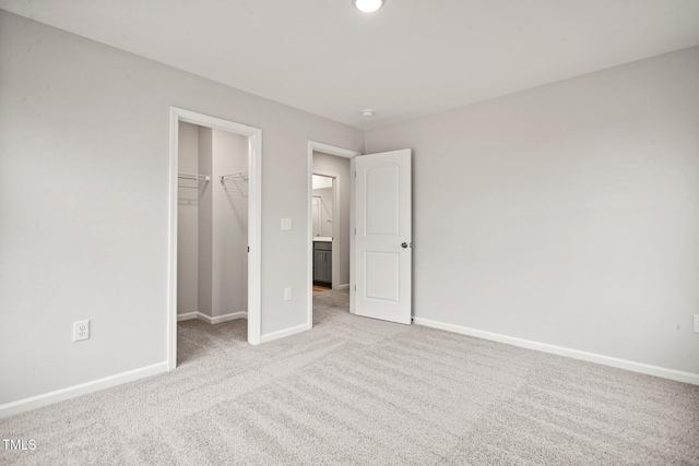 unfurnished bedroom featuring light colored carpet, a spacious closet, and a closet