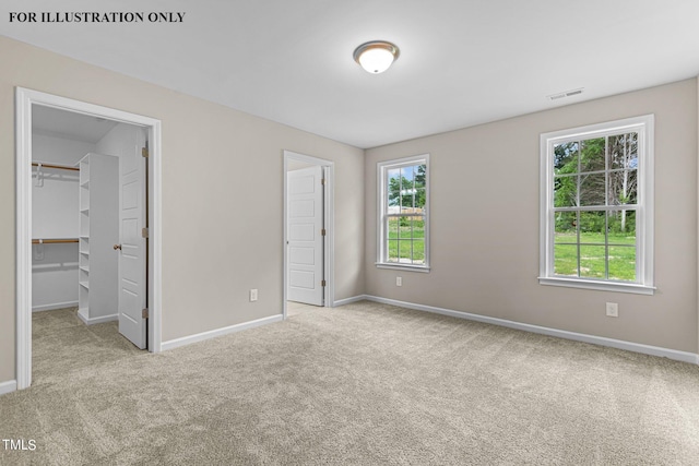 unfurnished bedroom featuring light carpet, a closet, and a walk in closet