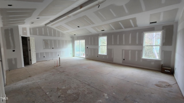 empty room with a wealth of natural light and lofted ceiling