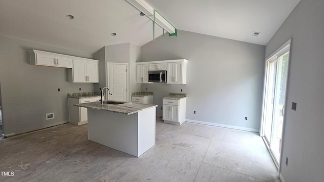 121 Tanglewood Dr Unit 8-J, Louisburg, NC 27549 - kitchen with stainless steel microwave, white cabinetry, an island with sink, a sink, and stone counters