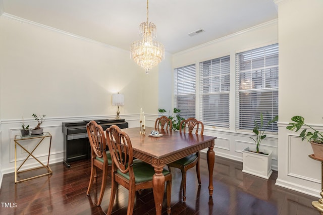 dining space with a chandelier, ornamental molding, and dark wood-type flooring