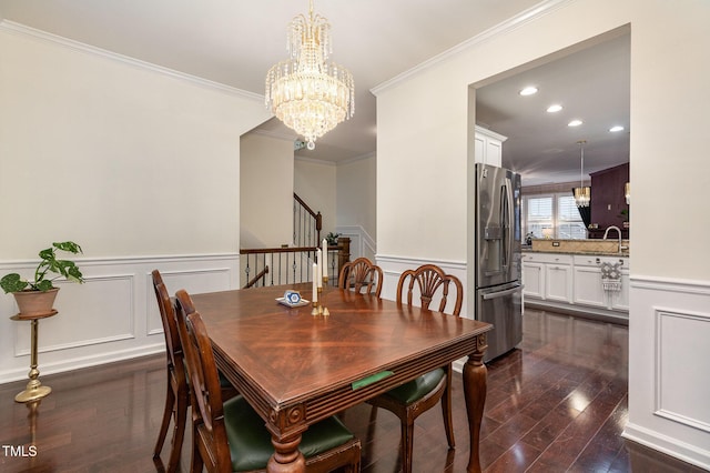 dining space featuring a notable chandelier, sink, ornamental molding, and dark wood-type flooring