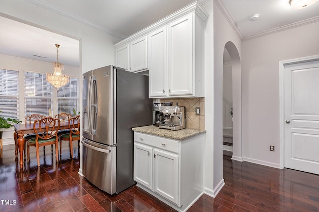 kitchen with stainless steel fridge, backsplash, white cabinetry, and light stone counters