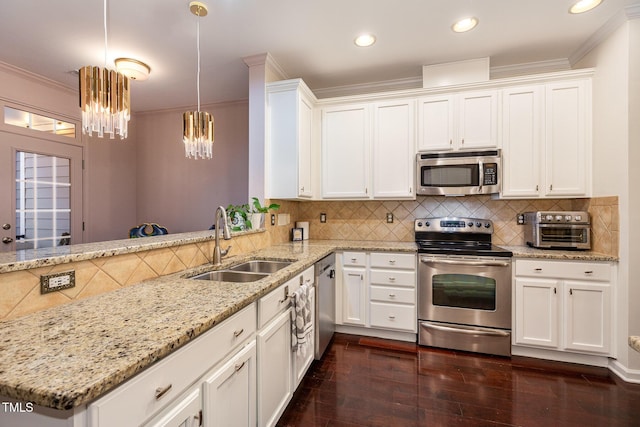 kitchen featuring kitchen peninsula, appliances with stainless steel finishes, tasteful backsplash, sink, and hanging light fixtures