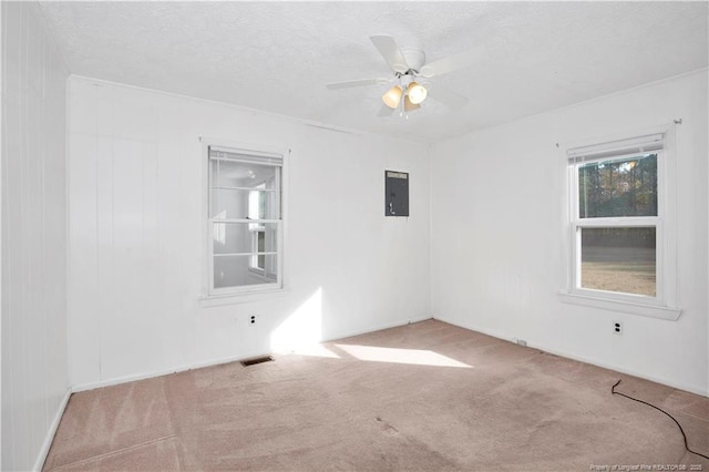 empty room with ceiling fan, light colored carpet, a textured ceiling, and electric panel