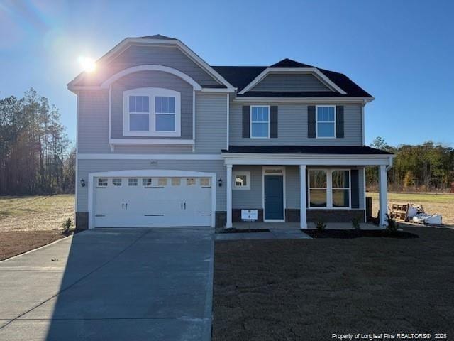 view of front of home with a garage, concrete driveway, a porch, and a front yard