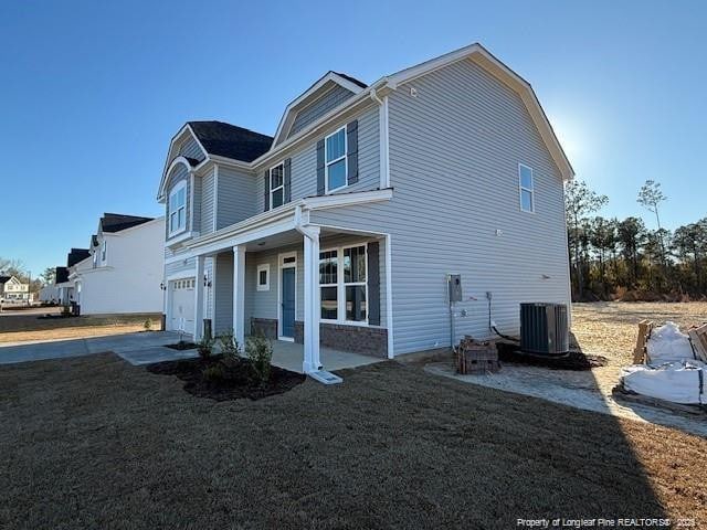 view of property exterior with a garage, a patio area, central AC, and a yard