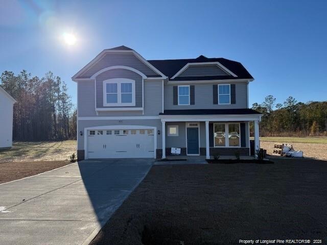 traditional home with driveway, a front lawn, a porch, and an attached garage