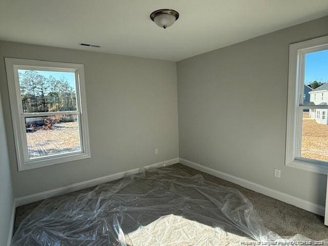 spare room with baseboards, visible vents, and a healthy amount of sunlight