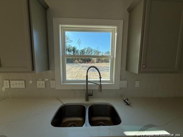 kitchen featuring gray cabinetry, a sink, and decorative backsplash