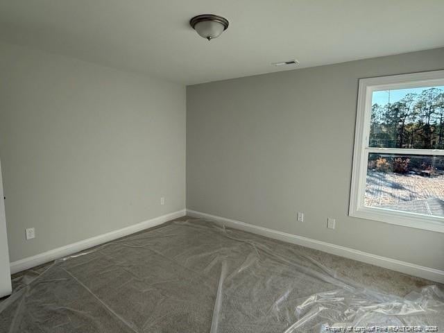 carpeted spare room with visible vents and baseboards