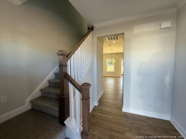 stairs with ornamental molding, wood finished floors, visible vents, and baseboards