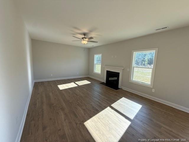 unfurnished living room with dark wood-style flooring, a fireplace with flush hearth, visible vents, and baseboards