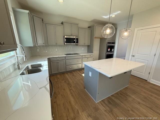 kitchen featuring decorative backsplash, stainless steel appliances, a sink, and gray cabinetry