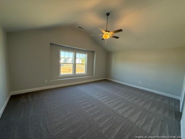 unfurnished room featuring lofted ceiling, a ceiling fan, visible vents, baseboards, and dark carpet