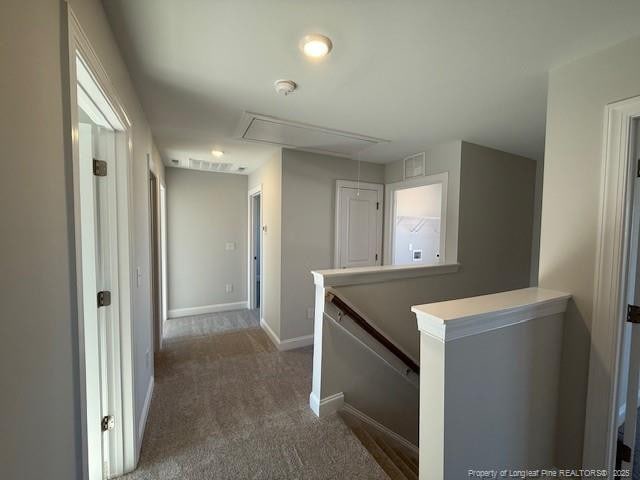 hallway with visible vents, baseboards, an upstairs landing, carpet, and attic access