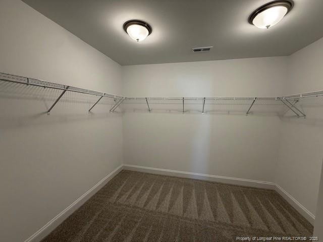 spacious closet featuring visible vents and dark carpet