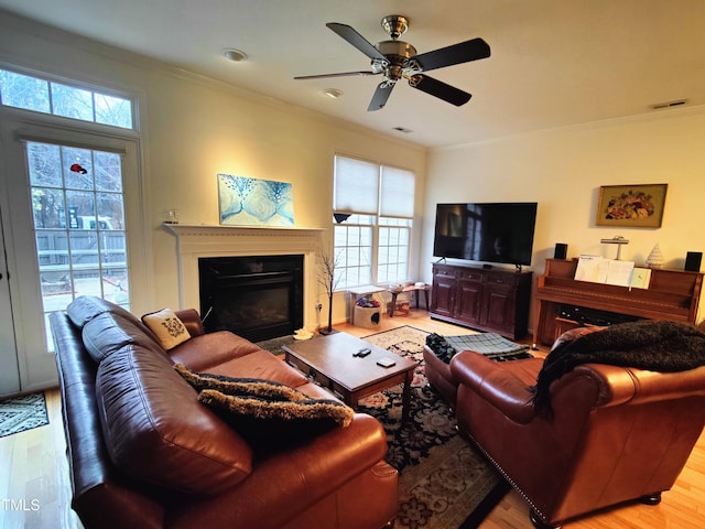 living room featuring plenty of natural light, light wood-type flooring, and ornamental molding