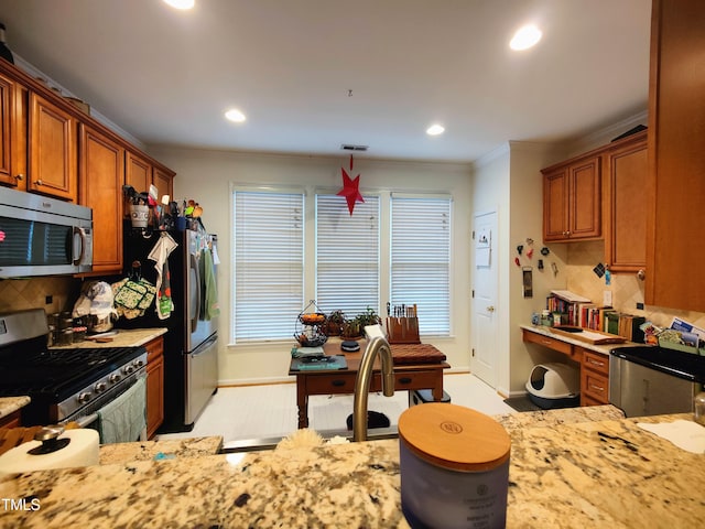 kitchen featuring light stone countertops, backsplash, crown molding, pendant lighting, and appliances with stainless steel finishes