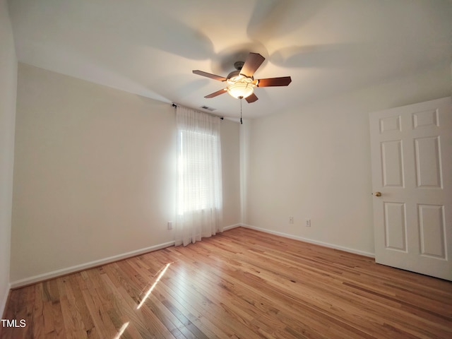 spare room featuring a ceiling fan, light wood-type flooring, visible vents, and baseboards