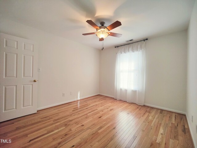 empty room featuring light wood finished floors, ceiling fan, visible vents, and baseboards