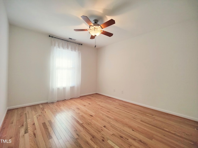 spare room with visible vents, light wood-type flooring, a ceiling fan, and baseboards