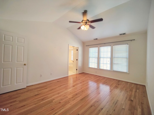 spare room with lofted ceiling, light wood finished floors, baseboards, and visible vents