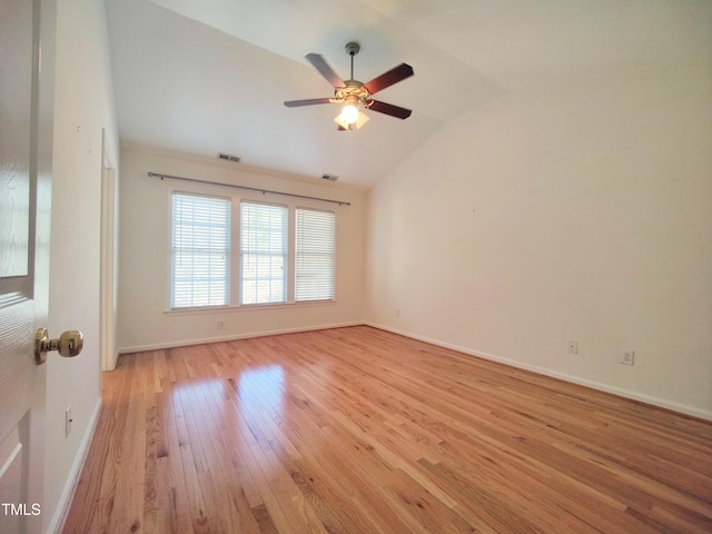 spare room with lofted ceiling, visible vents, light wood-style flooring, and baseboards