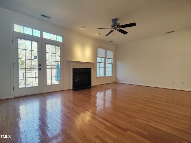 unfurnished living room with visible vents, crown molding, and wood finished floors