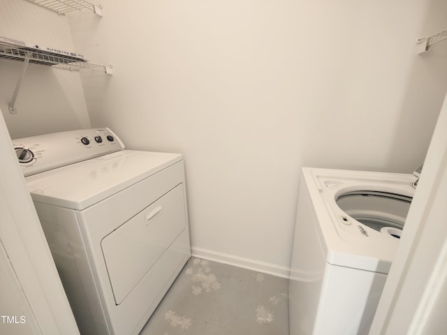 washroom featuring laundry area, baseboards, and washing machine and clothes dryer