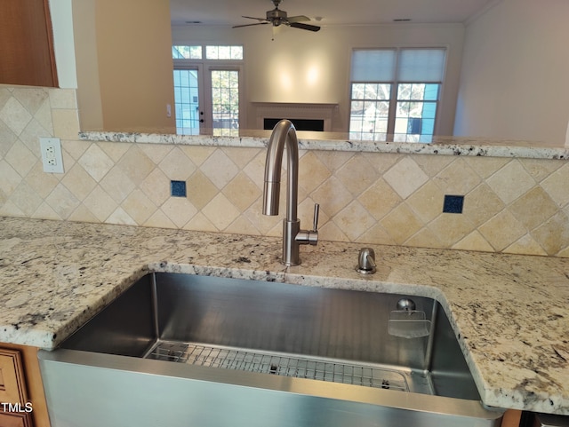 interior details featuring decorative backsplash, ceiling fan, ornamental molding, a fireplace, and a sink