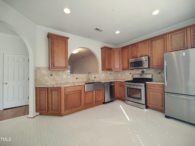 kitchen with visible vents, brown cabinetry, light wood-style flooring, stainless steel appliances, and a sink