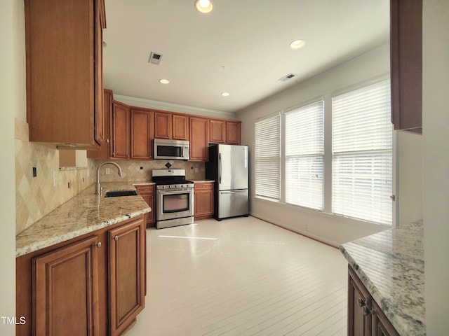 kitchen featuring stainless steel appliances, tasteful backsplash, visible vents, a sink, and light stone countertops