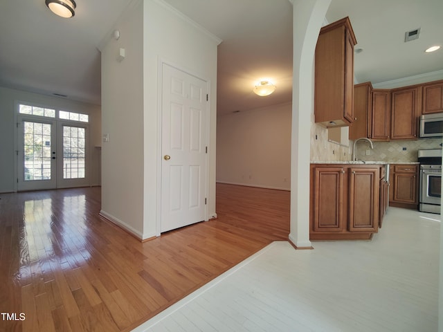 kitchen featuring stainless steel appliances, brown cabinets, and ornamental molding