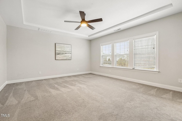 spare room featuring a tray ceiling, carpet floors, and ceiling fan