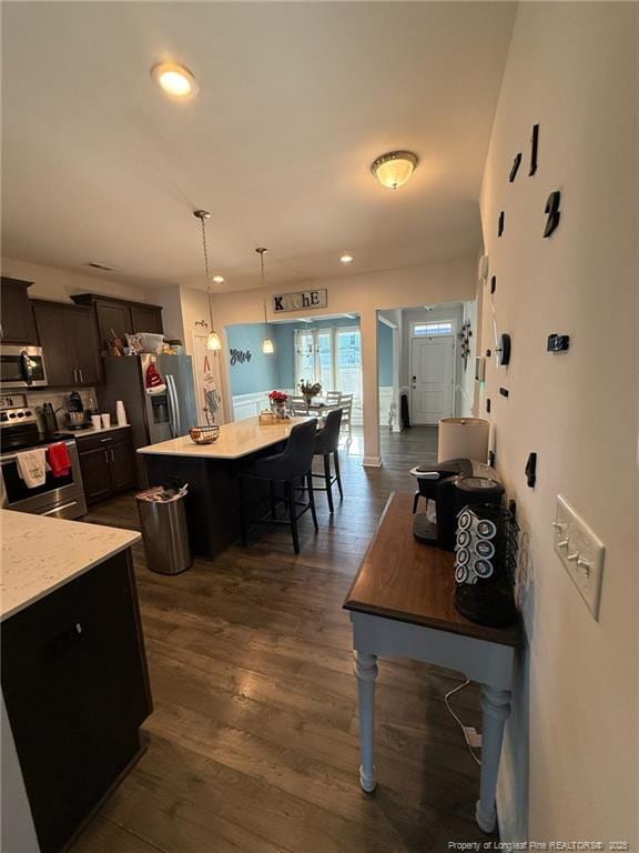 kitchen with decorative light fixtures, dark wood finished floors, recessed lighting, appliances with stainless steel finishes, and a kitchen island