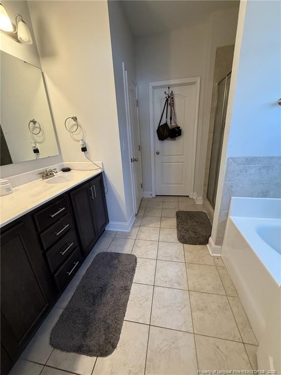 bathroom with vanity, baseboards, a bath, tile patterned floors, and a stall shower