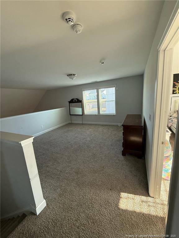 additional living space with carpet floors, lofted ceiling, and baseboards