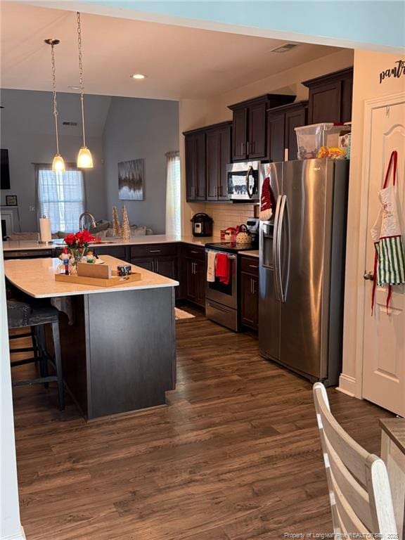 kitchen with stainless steel appliances, dark wood-type flooring, a peninsula, light countertops, and dark brown cabinets